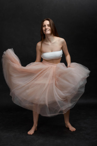 年轻的女孩穿着白色上衣和桃裙跳舞图片下载