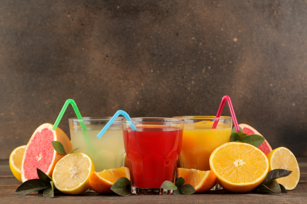 柑橘类果汁。棕色的木桌上放着柠檬、柚子、橙汁和新鲜水果。为文本留出空间。图片下载