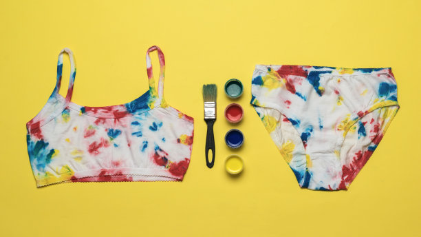 黄色背景上的织物颜料和一套扎染式内衣。图片下载