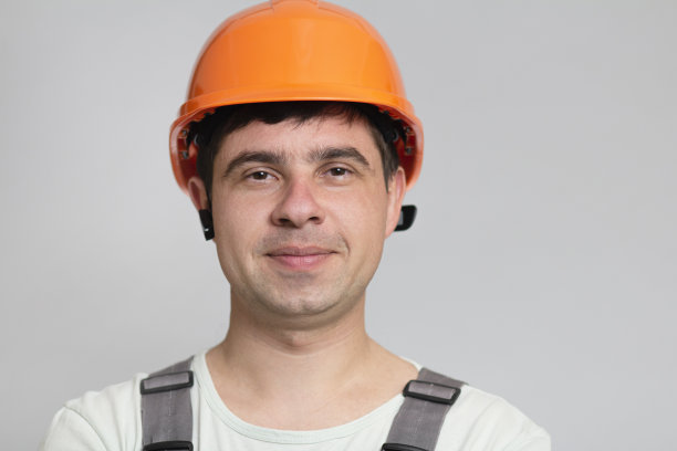 肖像的成功和快乐的建筑工人在一个头盔，脸的年轻工头在灰色的背景图片下载