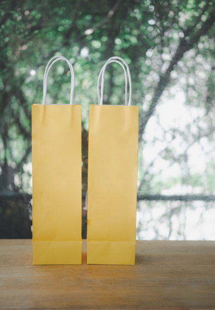 木桌上放置装有瓶柄的黄色纸袋图片下载