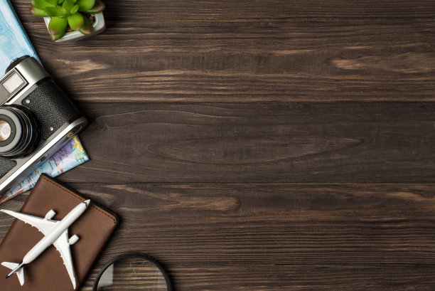 俯视图照片的飞机模型护照覆盖植物放大镜相机和地图上孤立的木桌背景与copyspace在右边图片下载