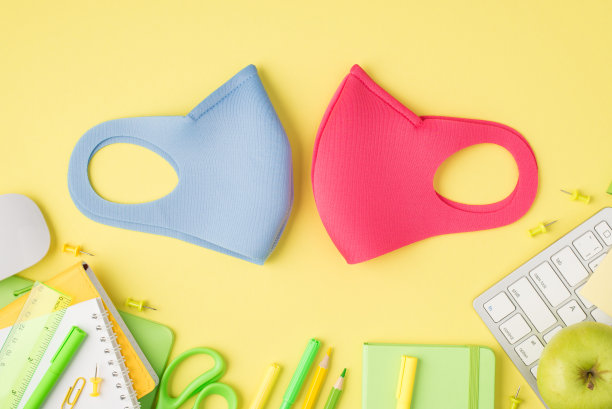 头顶上的照片两个面具，笔记本，钢笔，铅笔，毡尖，剪刀，尺子，回形针，苹果，电脑，鼠标和键盘孤立在黄色的背景与空白的空间图片下载