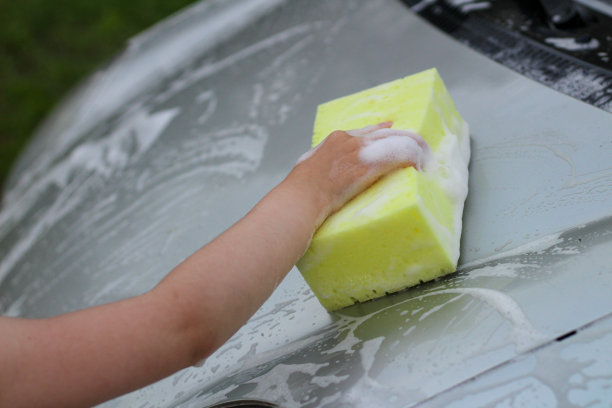 一个小孩用海绵擦拭汽车的引擎盖图片下载