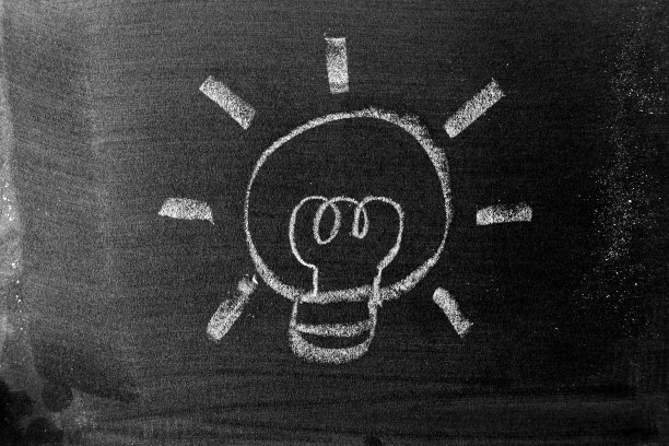 白色粉笔在黑板或黑板的背景上画灯泡形状(新想法或创意的概念)图片下载
