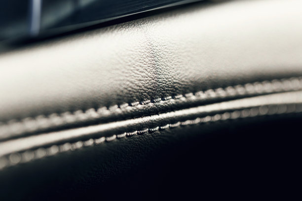 部分缝制皮革黑色皮革汽车内饰。现代豪华轿车黑色皮革内饰。汽车皮革内部细节与白色缝线。装饰缝。微距镜头图片下载