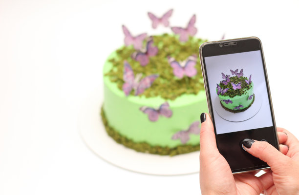 女人的手拿着一个手机，拍了一张漂亮的蛋糕的照片图片下载
