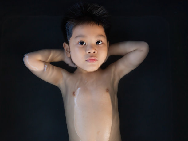 可爱的小男孩泡在黑色浴缸里图片下载