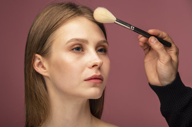 美丽的年轻女子在涂抹粉底。化妆师正在与华丽的模特工作。化妆、修指甲和化妆图片下载