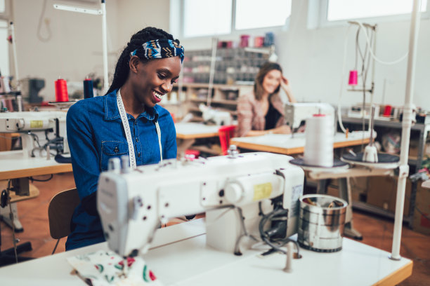 年轻的非洲时装设计师在她的车间里使用缝纫机图片下载
