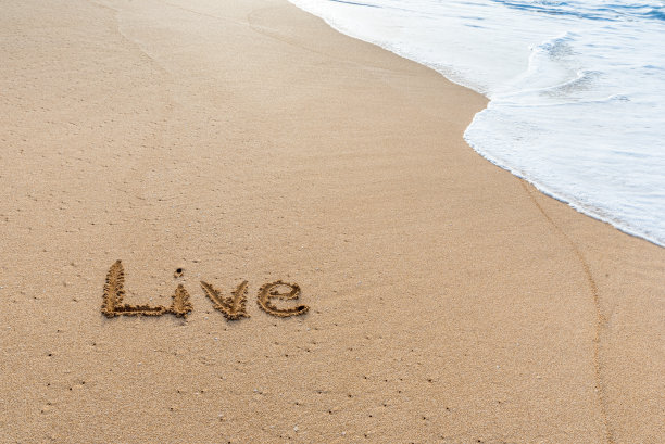 “活”写在沙滩上，用海浪冲刷着图片下载