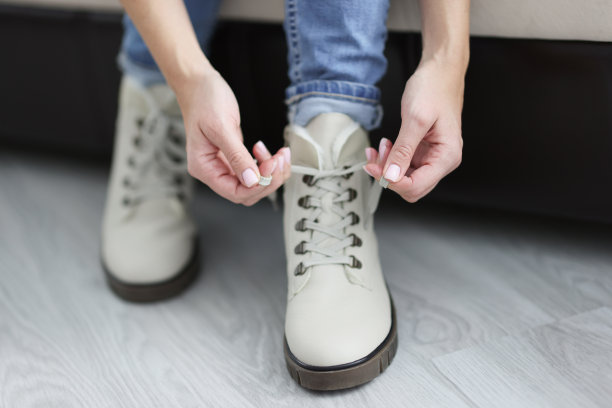 女人系鞋带在白色温暖的鞋子特写图片下载