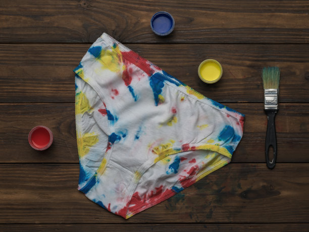 女式内裤扎染风格和深色木制背景上的油漆。图片下载