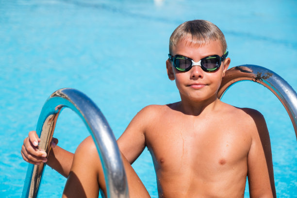 快乐男孩带着护目镜在游泳池里积极的生活方式图片下载