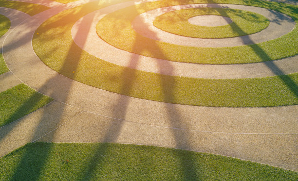 园林区域人造绿草皮和砾石铺装地面的圆形图案上的光影图片下载
