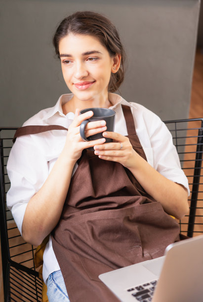 垂直角度的美丽的白人女咖啡师看起来茫然的咖啡店外，而放松在咖啡休息前的笔记本电脑图片下载