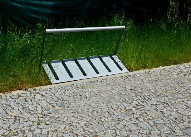 自行车轮架的灰色板金属管在草坪上的长方形，铺在城市的花岗岩立方体图片下载