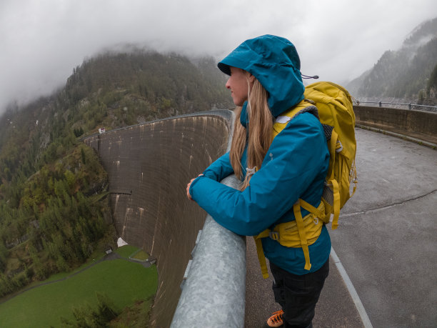 雨中徒步的女人，在水坝上行走图片下载
