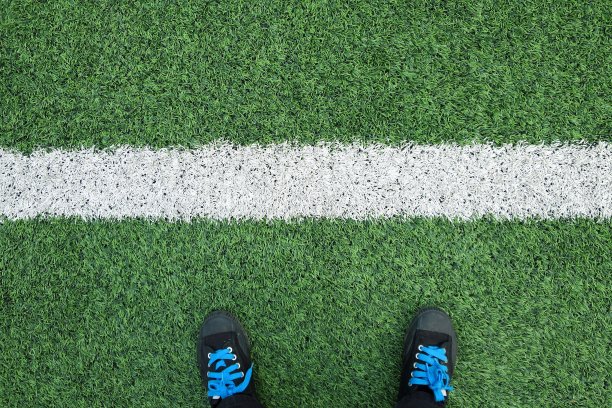 黑色运动鞋在足球或足球场上与白线。图片下载