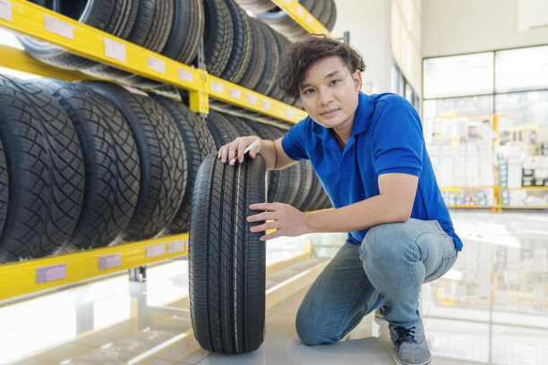 轮胎店。微笑的汽车修理工在轮胎商店的轮胎图片下载