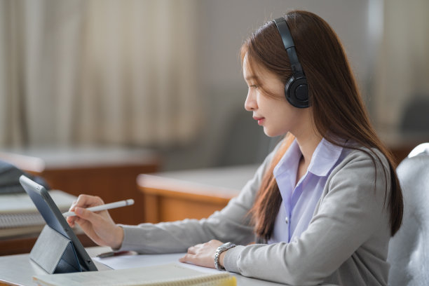 年轻的互动快乐的亚洲少女大学学生学习和展示她的课通过视频在一个数字平板电脑在教室独自一人。教育库存图片图片下载