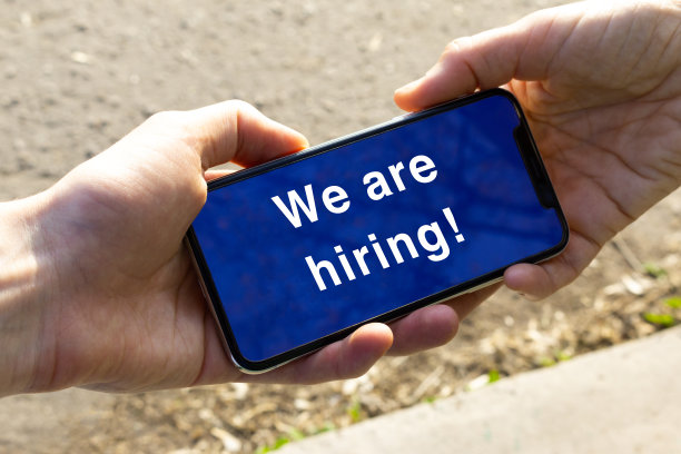 两只手拿着智能手机，屏幕上写着“我们正在招聘”。关于新职位空缺的留言图片下载