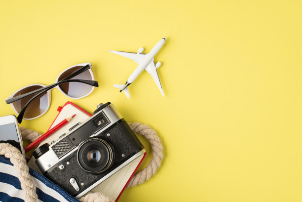 上面照片的太阳镜，手机袋，相机，笔记本，铅笔和飞机孤立在黄色的背景与空白图片下载