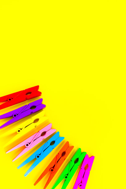 黄色背景上的彩色木衣夹。关闭，复制空间。极简主义，原创和创意的照片。是另一个。个性的概念。垂直墙纸智能手机。图片下载