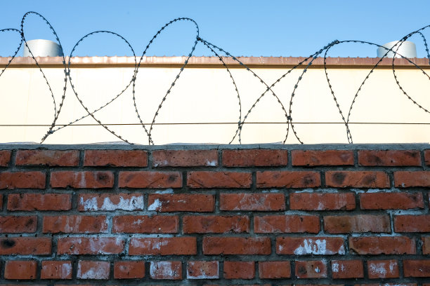 在蓝天的映衬下，有铁丝网的砖墙和灯光建筑图片下载