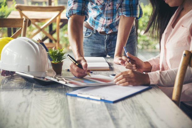 土建工程师团队在施工现场开会，与团队一起穿安全服，信任团队在桌上看蓝图，一起咨询安全安全帽，建设工程师概念图片下载