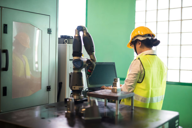 工厂工人用电脑控制机器手臂图片下载