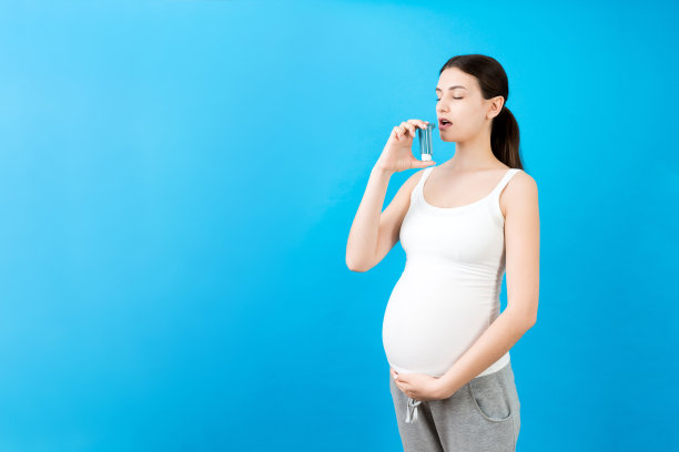孕妇手持哮喘吸入器防止发作在彩色背景与复制空间。未来的母亲患有呼吸道疾病。哮喘的概念图片下载