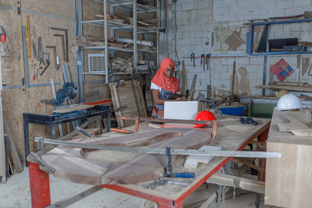 穆斯林女木匠在宽敞的木工车间使用笔记本电脑图片下载