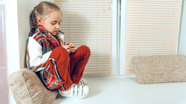 一个小女孩蹲着玩黄色的长颈鹿玩具。扎着辫子的女孩穿着红手裙图片下载