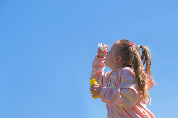 小女孩吹肥皂泡。活泼的孩子在公园散步。家庭生活方式，户外活动，和孩子一起度假。图片下载