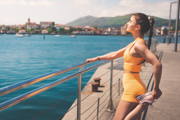 巴斯克地区亨达亚码头，一名身穿橙色服装的年轻女子伸展身体。图片下载