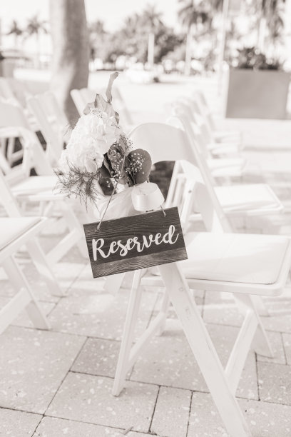 在南佛罗里达的一个经典户外婚礼上，白色户外椅子上有一个木制的“保留”标志和精致的白色花朵图片下载