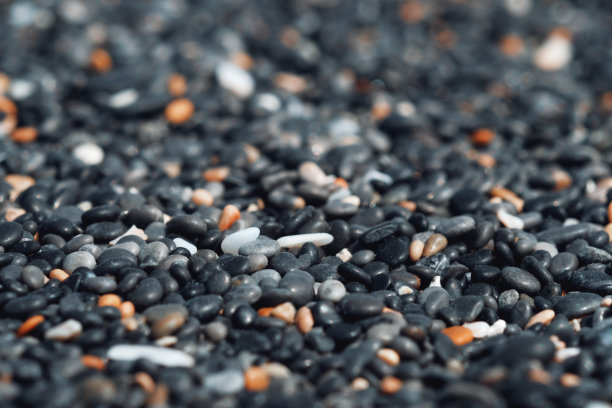 抽象的背景与黑色和橙色圆形的海卵石石纹理在岸边近距离地在朦胧的夕阳光线下，近距离地，自然的复制空间图片下载