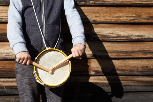 在木墙上敲着鼓和鼓槌的孩子图片下载