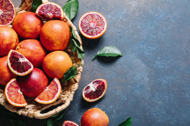 一堆血橙放在一个篮子里，放在一张蓝色的桌子上。平铺，俯视图，拷贝空间图片下载