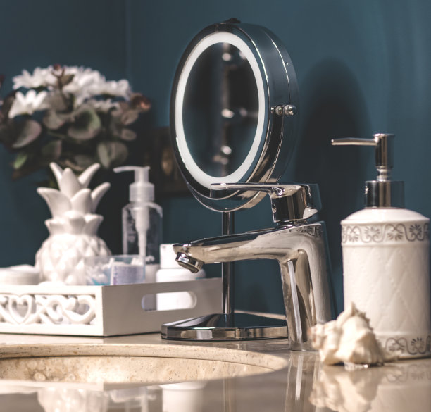 色彩新潮的浴室，洗涤区，卫生整洁。圆形金属镜，棉垫，耳棒，膏霜，液体肥皂在一个分配器。石材台面，白色毛巾。舒适的浴室内。图片下载