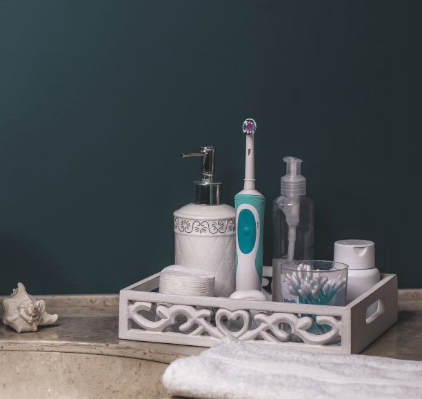 色彩新潮的浴室，洗涤区，卫生整洁。圆形金属镜，棉垫，耳棒，膏霜，液体肥皂在一个分配器。石材台面，白色毛巾。舒适的浴室内。图片下载