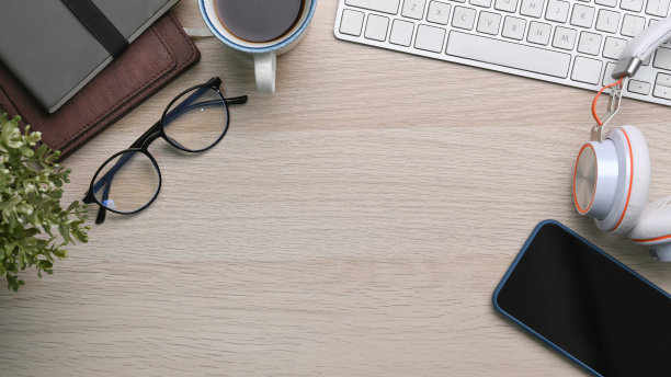 简单的工作空间，手机，眼镜，键盘，咖啡杯和笔记本放在木桌上。图片下载
