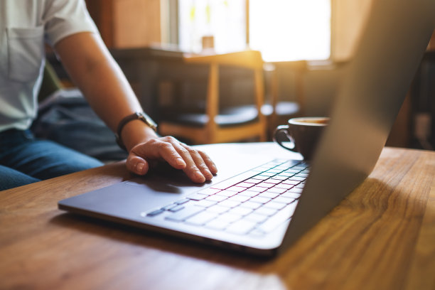 一位女士一边工作一边触摸桌子上的笔记本触控板图片下载