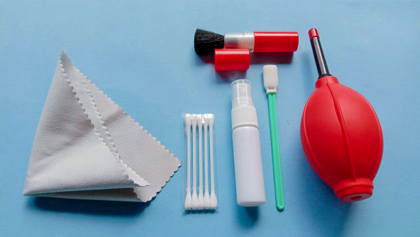 照片的相机清洁用品，如鼓风机，刷子，超细纤维布，水喷在蓝色背景图片下载