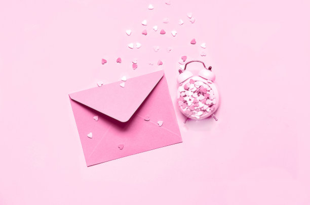 粉红色的爱心闹钟，粉红色的背景是信封。节日概念或浪漫爱情信息。单色。创意副本空间图片下载