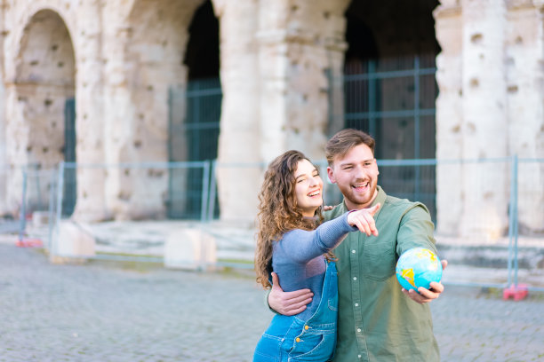 年轻的旅行者夫妇停了下来，女孩指着前方。快乐的游客参观著名的地标。蜜月旅行、旅游、爱情度假、度假旅游概念-形象图片下载