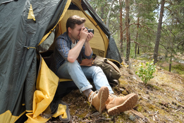 微笑的年轻游客坐在森林的旅游帐篷里拍摄照片图片下载