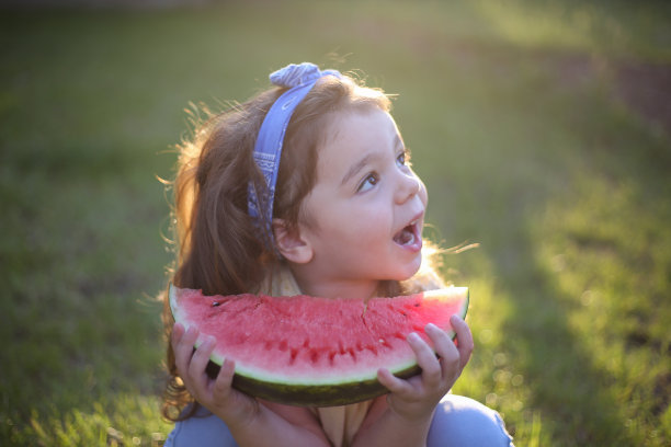 可爱的小女孩在吃新鲜的西瓜水果在花园库存照片图片下载