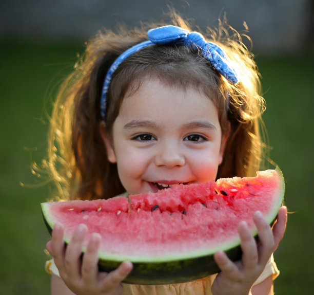 可爱的小女孩在吃新鲜的西瓜水果在花园库存照片图片下载